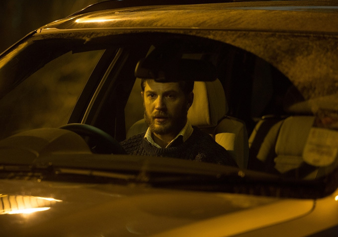 Tom Hardy sits in a car.