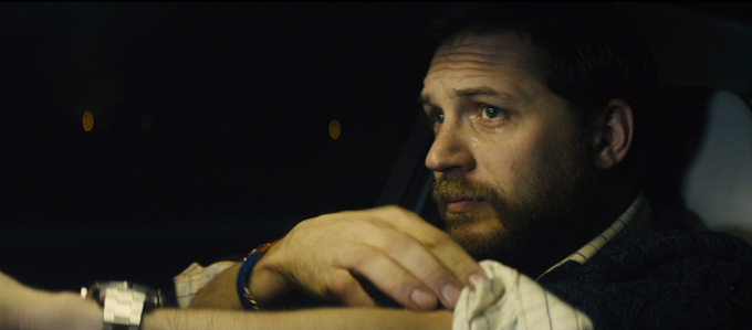 Tom Hardy still sits in a car.